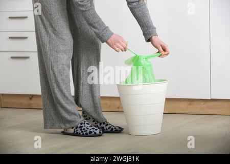 Femme au foyer jetant les ordures, prenant le sac poubelle en plastique de la poubelle dans l'appartement Banque D'Images