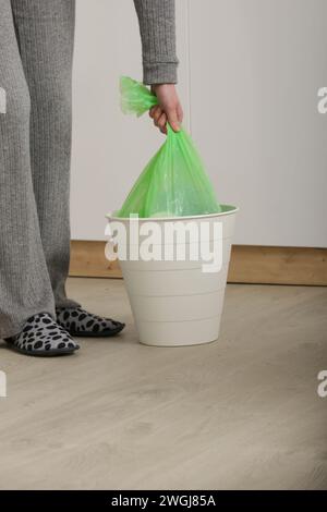 Femme au foyer jetant les ordures, prenant le sac poubelle en plastique de la poubelle dans l'appartement Banque D'Images