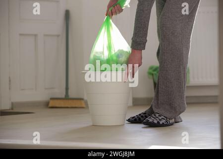 Femme au foyer jetant les ordures, prenant le sac poubelle en plastique de la poubelle dans l'appartement Banque D'Images