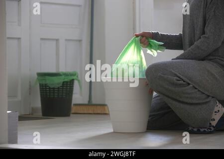 Femme au foyer jetant les ordures, prenant le sac poubelle en plastique de la poubelle dans l'appartement Banque D'Images