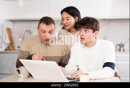 Une famille amicale regarde quelque chose ensemble sur Internet ou des chats vidéo via un ordinateur portable Banque D'Images
