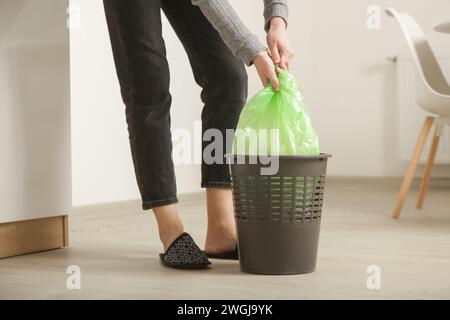 Femme au foyer jetant les ordures, prenant le sac poubelle en plastique de la poubelle dans l'appartement Banque D'Images