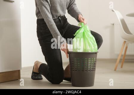 Femme au foyer jetant les ordures, prenant le sac poubelle en plastique de la poubelle dans l'appartement Banque D'Images