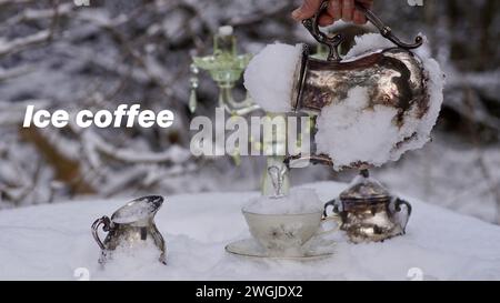 Une main tenant une cafetière argentée congelée, versant de la glace dans une tasse. Pichet à lait et sucre. Neige. Banque D'Images