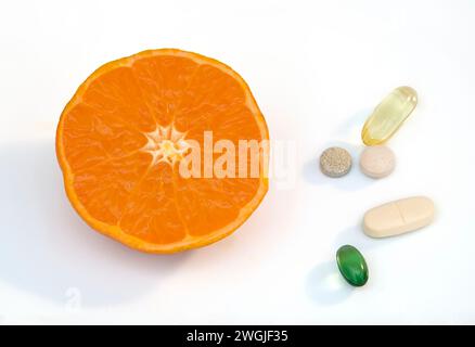 Studio shot de la moitié orange clémentine, qui sont une variété d'orange mandarine, affichée sur fond blanc avec un mélange de comprimé de vitamine Banque D'Images