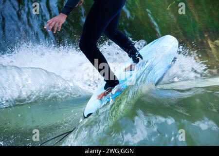 Partie du corps d'un surfeur surfant sur les écoulements de l'eau d'une rivière Banque D'Images