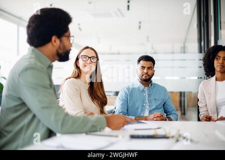 Une équipe diversifiée écoute attentivement, un employé masculin faisant valoir son point de vue, ce qui reflète une séance de brainstorming engagée et une culture de communication ouverte. Concept d'une atmosphère de travail ciblée Banque D'Images