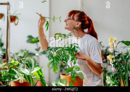 Jeune femme aux cheveux rouges caucasien fleuriste, amoureux des plantes, profiter de l'entretien des plantes d'intérieur de maison dans des pots, Banque D'Images