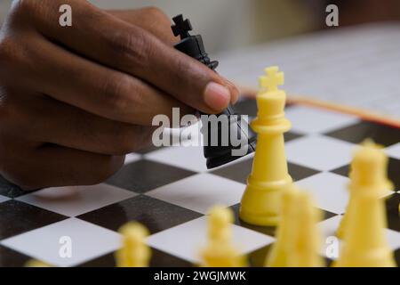 Gros plan de la main d'un homme noir plaçant une pièce d'échecs en toute confiance, mettant en évidence la pensée stratégique et la prise de décision calculée Banque D'Images