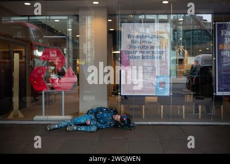 Homme sans-abri repose sur le trottoir de Victoria Street dans le centre de Londres, Angleterre, Royaume-Uni Banque D'Images