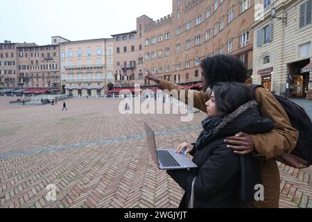 Joyeux jeune couple multiethnique de touristes avec carte visitant la ville historique de Sienne, Toscane, Italie Banque D'Images