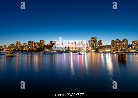 Une photo longue exposition à l'heure bleue de la Skyline de Vancouver depuis False Creek avec le BC place Stadium illuminé. Banque D'Images