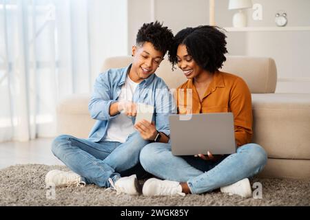 Un jeune couple s'engage avec la technologie dans un espace de vie lumineux, le partage Banque D'Images