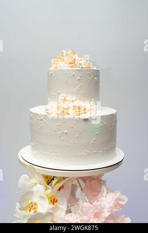 Gâteau de mariage blanc à deux niveaux décoré de fleurs. Banque D'Images
