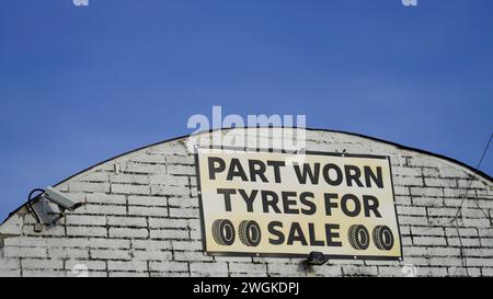 Barry, Vale of Glamorgan, pays de Galles 02 février 2024 : vente et montage de pneus annoncés dans une unité industrielle vintage voûtée sur un quai. Mur de briques blanches sale Banque D'Images