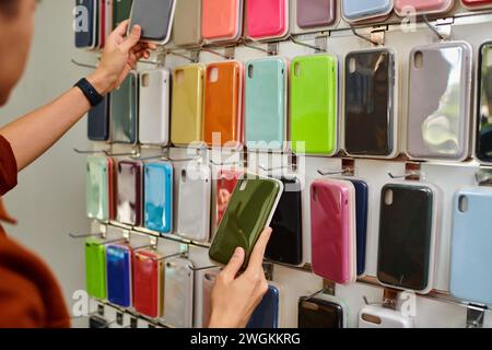 vue rognée du vendeur choisissant l'étui de téléphone coloré de l'assortiment dans le magasin privé Banque D'Images