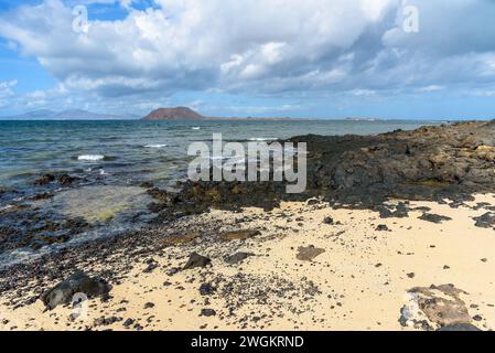 Vue de la côte volcanique rocheuse de Fuerteventura à Corralejo avec l'île de Lobos en arrière-plan Banque D'Images