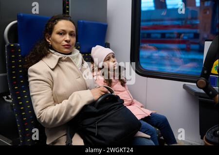 Belle famille, mère et fille assis près de la fenêtre passager dans un train à grande vitesse se déplaçant d'une ville à l'autre. Les gens. Style de vie. Utilisation de rai Banque D'Images