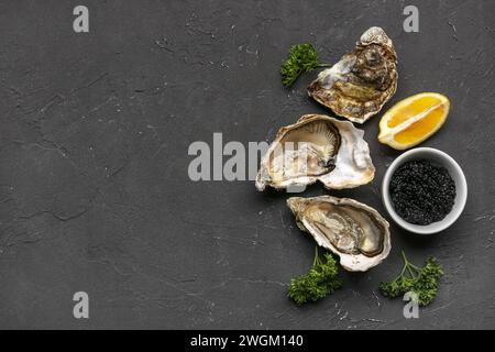 Huîtres savoureuses au citron et au caviar sur fond noir Banque D'Images