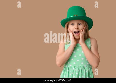 Petite fille choquée dans le chapeau de leprechaun sur fond brun. Prog Célébration de la fête de Patrick Banque D'Images