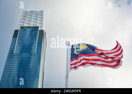 Kuala Lumpur, Malaisie - 28 janvier 2024 : drapeau malaisien sur un poteau ondulant dans le ciel avec le bâtiment Exchange 106 derrière lui. Banque D'Images