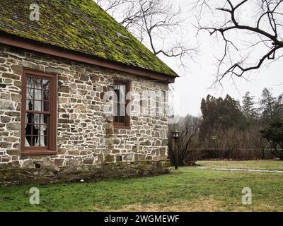 Vieille maison en pierre avec toit en mousse et branche d'arbre noueux dans la ville historique de Virginie. Banque D'Images