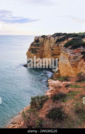 Les gens debout sur les falaises au-dessus de l'océan Atlantique un jour d'hiver dans le sud du Portugal. Banque D'Images