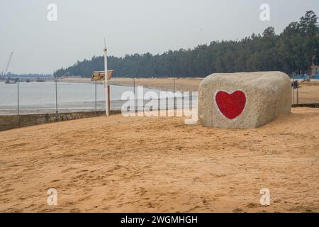 Une pierre romantique avec un coeur rouge gravé sur la plage au bord de la mer Banque D'Images