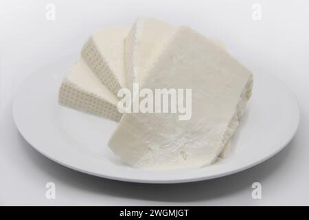 TRANCHES DE FROMAGE FRAIS SUR UNE ASSIETTE AVEC FOND ISOLÉ Banque D'Images