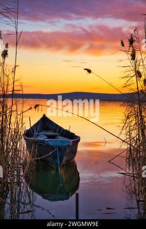 Un vieux bateau en bois flottant au-dessus d'un lac au lever du soleil Banque D'Images