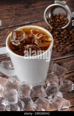 Une tasse de café Iced Americano avec des glaçons placés sur une table en bois dans un café Banque D'Images