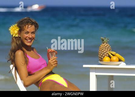 prettyauburn cheveux jeune femme profil face naturel drinkung jus de fruits vacances d'été ciel bleu et fond de plage Banque D'Images