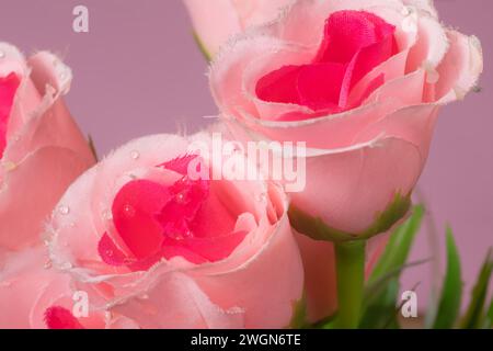 Une belle rose artificielle en gros plan sur un fond rose. Banque D'Images
