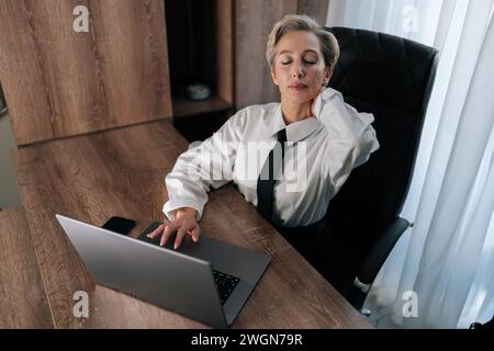 Portrait d'une femme d'affaires d'âge moyen fatiguée souffrant de douleurs au cou, nerfs pincés, muscles douloureux tendus, ostéochondrose cervicale. Femelle fatiguée Banque D'Images