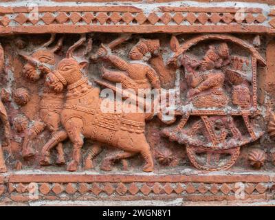 Vue rapprochée de la scène de terre cuite sculptée avec des hommes chevauchant un chariot de taureau sur l'ancien temple Govinda dans le complexe religieux de Puthia, Rajshahi, Bangladesh Banque D'Images