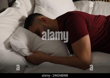 Homme triste cachant le visage dans l'oreiller sur le lit à la maison Banque D'Images