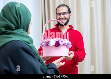 Comme surprise dans leur maison, un homme musulman heureux donne des roses à sa mère Banque D'Images