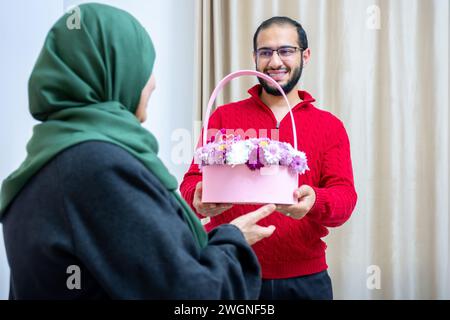 Comme surprise dans leur maison, un homme musulman heureux donne des roses à sa mère Banque D'Images