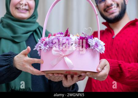 Comme surprise dans leur maison, un homme musulman heureux donne des roses à sa mère Banque D'Images