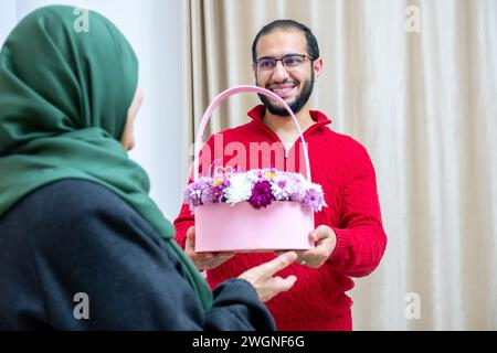 Comme surprise dans leur maison, un homme musulman heureux donne des roses à sa mère Banque D'Images