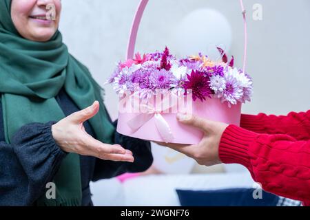 Comme surprise dans leur maison, un homme musulman heureux donne des roses à sa mère Banque D'Images