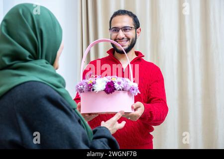 Comme surprise dans leur maison, un homme musulman heureux donne des roses à sa mère Banque D'Images