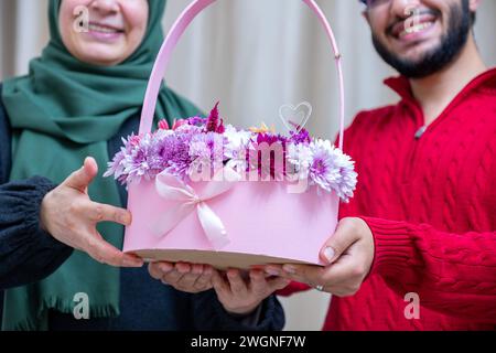 Comme surprise dans leur maison, un homme musulman heureux donne des roses à sa mère Banque D'Images