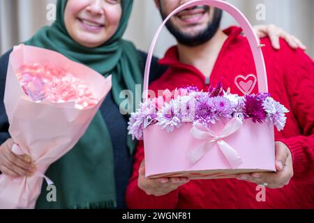 Comme surprise dans leur maison, un homme musulman heureux donne des roses à sa mère Banque D'Images