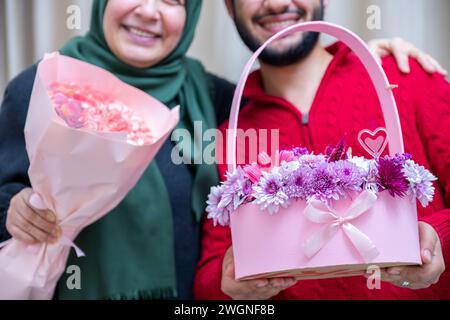 Comme surprise dans leur maison, un homme musulman heureux donne des roses à sa mère Banque D'Images