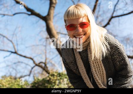 Jeune fille hippie amusante heureuse montrant la langue à la caméra pour le plaisir et faire des visages drôles tout en portant des lunettes de soleil fraîches. Femme féminine attrayante appréciant Banque D'Images