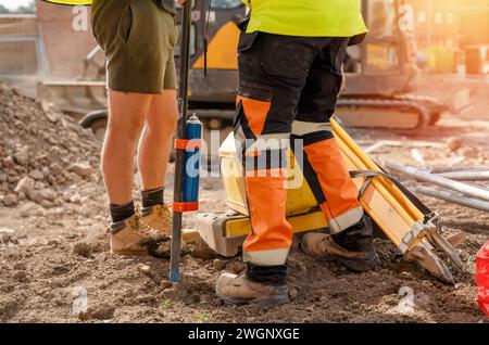 Travailleurs portant des bottes de sécurité ayant une courte discussion de planification sur le chantier de construction ou sur un lieu de travail à haut risque. Photo conceptuelle de la scène de travail de sécurité industrielle Banque D'Images