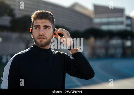 Un homme portant un maillot de sport noir, portant des écouteurs Banque D'Images