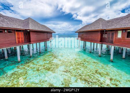 Vue panoramique sur les villas aquatiques aux Maldives avec une eau immaculée turquoise et un ciel orageux spectaculaire Banque D'Images