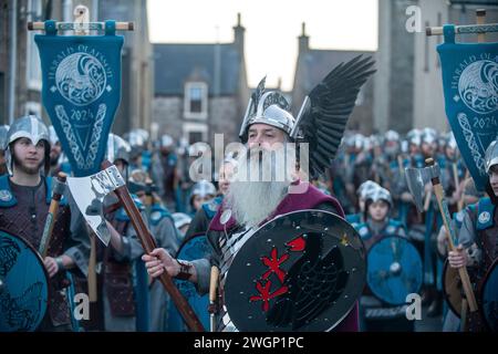 Les membres de la Jarl Squad 2024 défilent à travers Lerwick sur les îles Shetland pendant le festival Up Helly AA. Les filles de première année étaient dans Jarl Squad. Banque D'Images